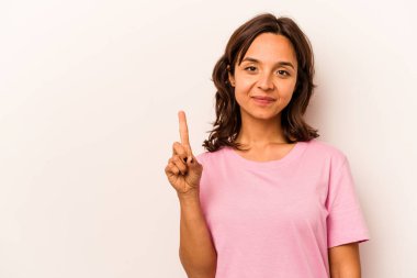 Beyaz arka planda izole edilmiş genç İspanyol kadın bir numarayı parmağıyla gösteriyor..