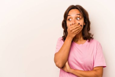 Latin kökenli genç bir kadın beyaz arka planda izole edilmiş. Düşünceli bir şekilde bir fotokopi odasına bakıyor. Ağzını eliyle kapatıyor..