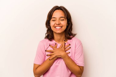 Young hispanic woman isolated on white background laughs happily and has fun keeping hands on stomach.