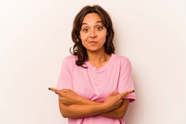 Beyaz arka planda izole edilmiş genç İspanyol kadın iki seçenek arasında seçim yapmaya çalışıyor..