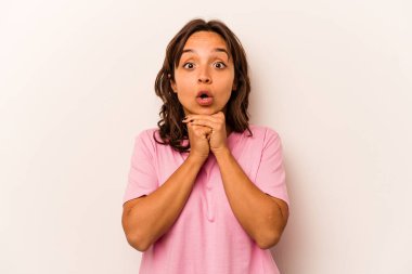 Latin kökenli genç bir kadın beyaz arka planda izole edilmiş şans için dua ediyor, şaşırmış ve ağzı açık bir şekilde önüne bakıyor..