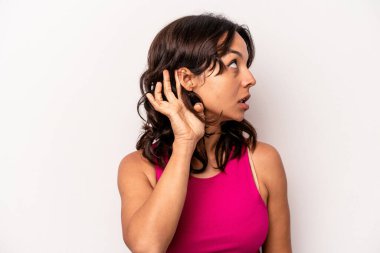 Beyaz arka planda izole edilmiş genç İspanyol kadın bir dedikoduyu dinlemeye çalışıyor..