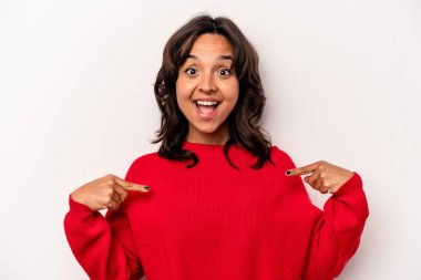 Beyaz arka planda izole edilmiş genç İspanyol kadın parmağını göstererek şaşırdı, geniş bir gülümsemeyle..