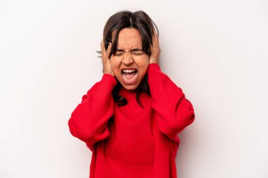 Latin kökenli genç bir kadın, beyaz arka planda izole edilmiş, kulaklarını elleriyle kapatmış, yüksek sesle sesler duymamaya çalışıyor..