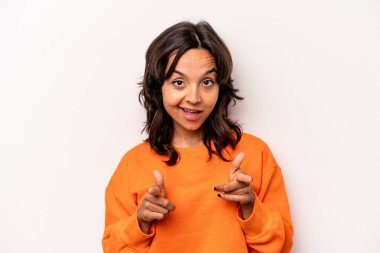 Beyaz arka planda izole edilmiş genç İspanyol kadın parmaklarıyla ön tarafı işaret ediyor..