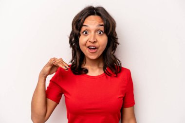 Beyaz arka planda izole edilmiş genç İspanyol kadın bir şeye gülüyor, elleriyle ağzını kapatıyor..