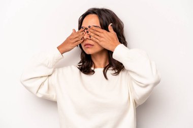 Beyaz arka planda izole edilmiş genç İspanyol kadın elleriyle gözlerini kapatmaktan korkuyor..