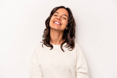 Beyaz arka planda izole edilmiş genç İspanyol kadın gevşemiş ve mutlu bir şekilde gülüyor, boynunda dişlerini gösteriyor..