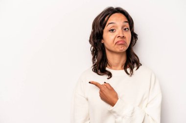 Beyaz arka planda izole edilmiş genç İspanyol kadın gülümsüyor ve boş alanda bir şeyler gösteriyor..