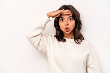 Beyaz arka planda izole edilmiş genç İspanyol kadın uzaklara bakıyor ve elini alnına koyuyor..