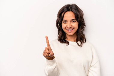 Beyaz arka planda izole edilmiş genç İspanyol kadın bir numarayı parmağıyla gösteriyor..