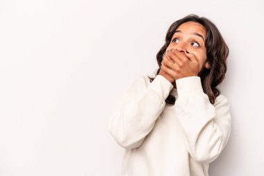 Latin kökenli genç bir kadın beyaz arka planda izole edilmiş. Düşünceli bir şekilde bir fotokopi odasına bakıyor. Ağzını eliyle kapatıyor..