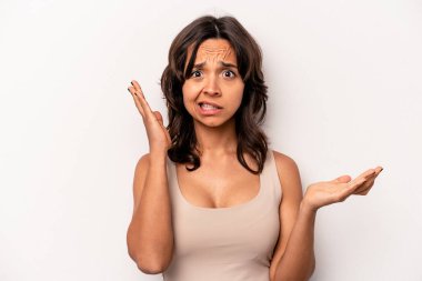 Beyaz arka planda izole edilmiş genç İspanyol bir kadın. Kafası karışmış ve omuz silkiyor. Kopya alanını tutmak için..