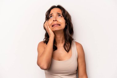 Beyaz arka planda izole edilmiş genç İspanyol kadın yorgun ve uykulu ellerini başının üstünde tutuyor..