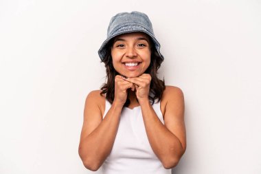 Beyaz arka planda izole edilmiş genç İspanyol kadın ellerini çenesinin altında tutuyor ve mutlu bir şekilde yan tarafa bakıyor..