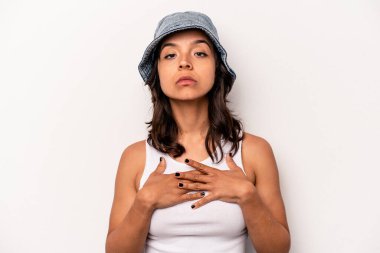 Beyaz arka planda izole edilmiş genç İspanyol kadın yemin ediyor, elini göğsüne koyuyor..