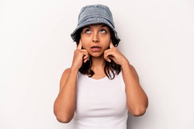Beyaz arka planda izole edilmiş, kulaklarını parmaklarıyla kapatan, stresli ve çaresiz genç İspanyol kadın yüksek sesli bir ortam tarafından..