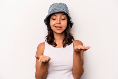 Beyaz arka planda izole edilmiş genç İspanyol kadın elinde avuç içi bir şeyle kameraya sunuyor..