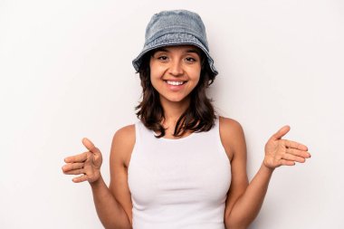 Beyaz arka planda izole edilmiş genç İspanyol kadın iki eliyle bir şey tutuyor, ürün sunumu..