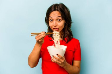 Mavi arka planda izole edilmiş erişte yiyen genç İspanyol kadın.