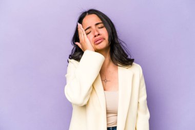 Mor arka planda izole edilmiş genç İspanyol kadın yorgun ve uykulu ellerini başının üstünde tutuyor.. 