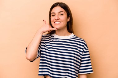 Bej arka planda izole edilmiş genç İspanyol kadın parmakları olan bir cep telefonu hareketi gösteriyor..