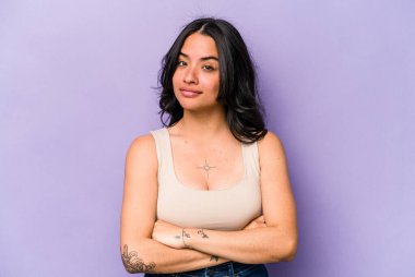 Genç İspanyol kadın mor arka planda izole edilmiş mutsuz bir şekilde iğneleyici bir ifadeyle kameraya bakıyor..