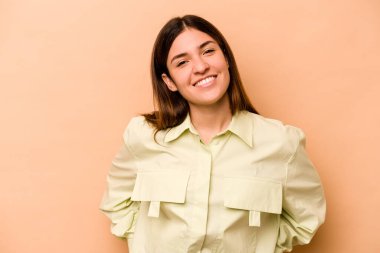 Genç İspanyol kadın bej arka planda izole edilmiş mutlu, güler yüzlü ve neşeli.