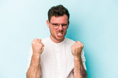 Mavi arka planda izole edilmiş genç beyaz adam gergin elleriyle çığlık atıyor..
