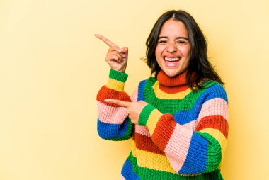 Sarı arka planda izole edilmiş genç İspanyol kadın işaret parmağıyla işaret ettiği için heyecanlı..