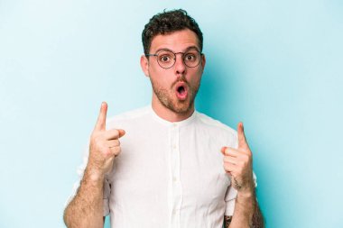 Mavi arka planda izole edilmiş beyaz bir adam ağzı açık bir şekilde üst tarafı işaret ediyor..