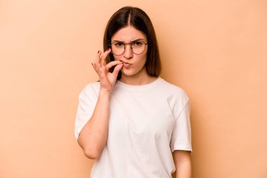 Bej arka planda izole edilmiş genç İspanyol kadın parmakları dudaklarında bir sır saklıyor..