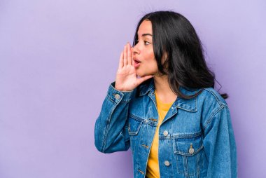 Mor arka planda izole edilmiş genç İspanyol kadın gizli bir sıcak fren haberi veriyor ve yan bakıyor.