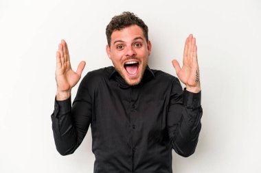 Beyaz arka planda izole genç beyaz adam hoş bir sürpriz alıyor, heyecanlı ve el kaldırıyor..