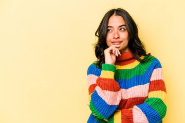 Sarı arka planda izole edilmiş genç İspanyol kadın rahatlamış bir şeyin fotokopi odasına baktığını düşünüyor..