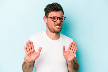 Mavi arka planda izole edilmiş genç beyaz adam tiksinti belirtisi gösteren birini reddediyor..