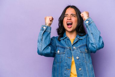Mor arka planda izole edilmiş genç İspanyol kadın zaferden sonra yumruk kaldırıyor, kazanan konsept..