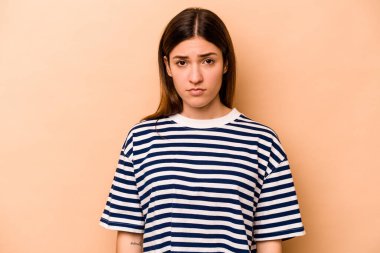 Genç İspanyol kadın bej arka planda izole edilmiş üzgün, ciddi yüzlü, mutsuz ve hoşnutsuz..