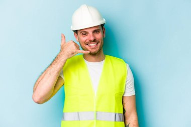 Genç beyaz adam mavi arka planda izole edilmiş. Parmakları olan bir cep telefonu hareketi gösteriyor..