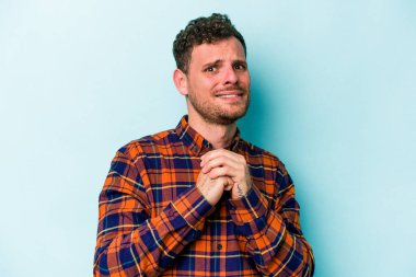 Kafkasyalı genç adam mavi arka planda izole edilmiş korkmuş ve korkmuş..