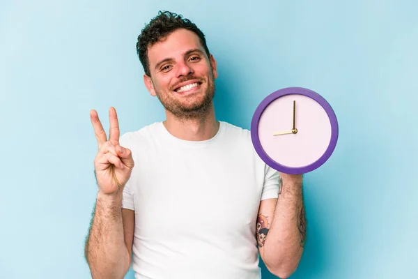 Young Caucasian Man Holding Clock Isolated Blue Background Joyful Carefree — Stock Fotó