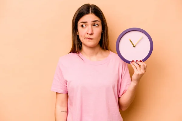 Junge Hispanische Frau Hält Eine Uhr Isoliert Auf Beigem Hintergrund — Stockfoto