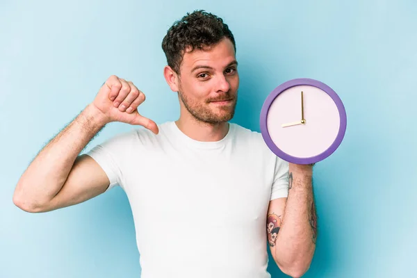 Jonge Blanke Man Met Een Klok Geïsoleerd Blauwe Achtergrond Voelt — Stockfoto