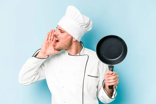 年轻的高加索厨师手持被蓝色背景隔离的飞盘大喊着 手牵着手掌靠近张开的嘴 — 图库照片