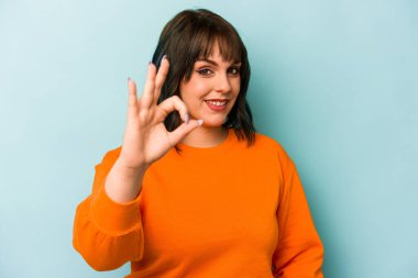 Kafkasyalı genç bir kadın mavi arka planda izole edilmiş neşeli ve kendinden emin..