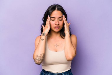 Mor arka planda izole edilmiş genç İspanyol kadın başı ağrıyor, yüzüne dokunuyor..