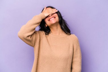 Mor arka planda izole edilmiş genç İspanyol kadın ellerini başının üstünde tutarak neşe içinde gülüyor. Mutluluk kavramı.