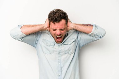 Beyaz arka planda izole edilmiş genç beyaz bir adam kulakları kulaklarıyla kapatıyor ve çok ses duymamaya çalışıyor..