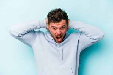 Genç beyaz adam mavi arka planda izole edilmiş bağırıyor, çok heyecanlı, tutkulu, bir şeyden memnun..