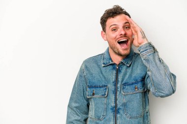 Beyaz arka planda izole genç beyaz adam yüksek sesle bağırıyor, gözleri açık ve elleri gergin tutuyor..